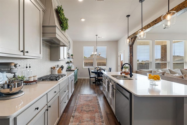 kitchen with appliances with stainless steel finishes, dark hardwood / wood-style flooring, sink, plenty of natural light, and an island with sink