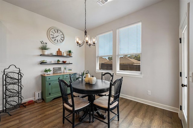 dining space with dark wood-type flooring and an inviting chandelier