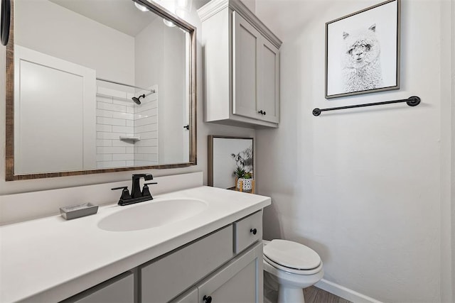 bathroom featuring a tile shower, vanity, and toilet