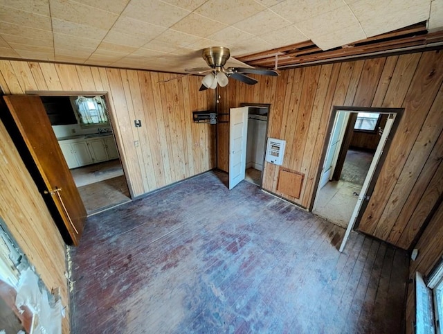 unfurnished bedroom featuring wooden walls, ceiling fan, connected bathroom, dark hardwood / wood-style flooring, and heating unit