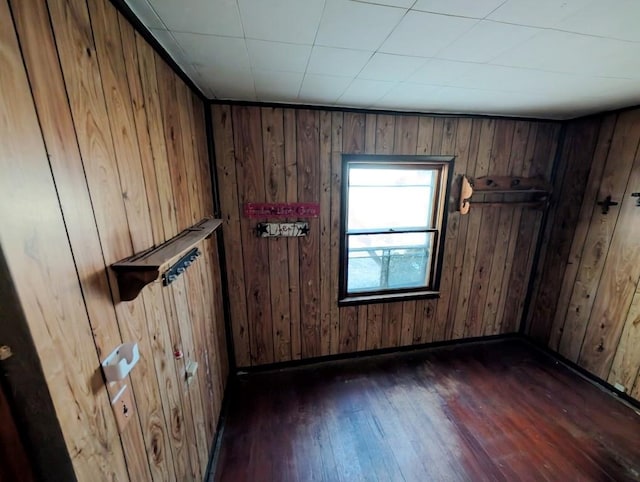 unfurnished room featuring dark hardwood / wood-style flooring and wooden walls