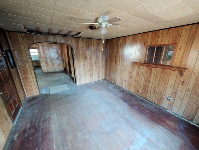 spare room featuring light wood-type flooring, ceiling fan, and wooden walls