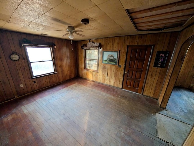 unfurnished room featuring dark hardwood / wood-style flooring, ceiling fan, and wood walls