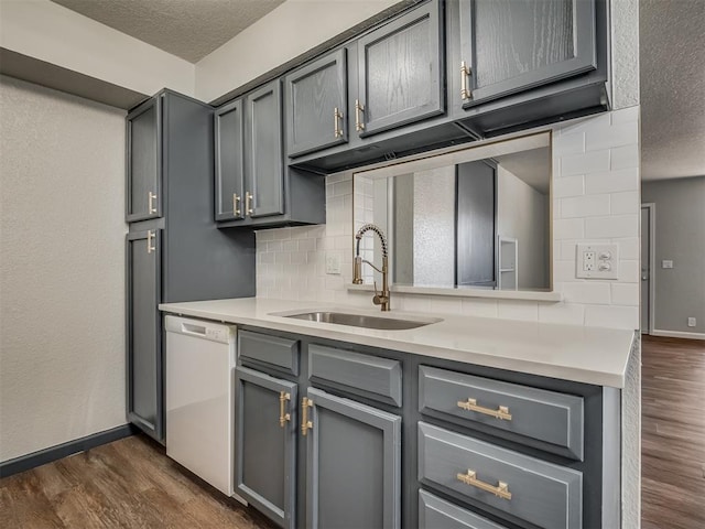 kitchen featuring tasteful backsplash, gray cabinets, dishwasher, and sink