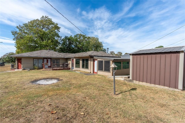 rear view of property with a yard and a storage unit