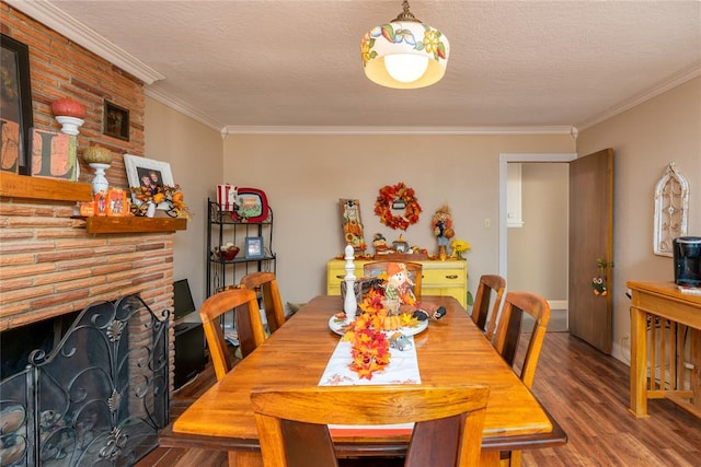 dining area featuring hardwood / wood-style floors, a textured ceiling, a brick fireplace, and ornamental molding