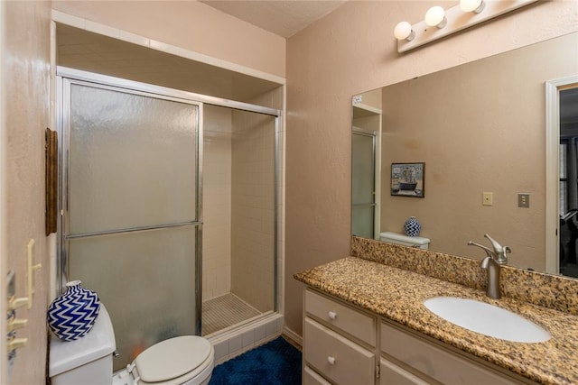 bathroom with vanity, a shower with shower door, and toilet