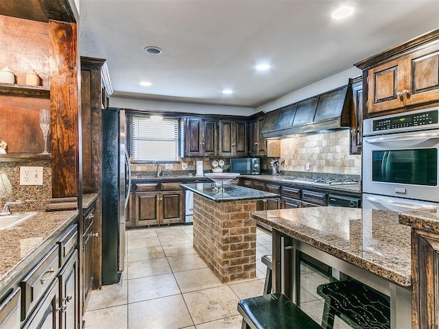 kitchen featuring appliances with stainless steel finishes, a center island, dark stone counters, and custom exhaust hood