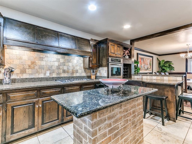 kitchen featuring backsplash, dark stone counters, a breakfast bar, stainless steel appliances, and a center island