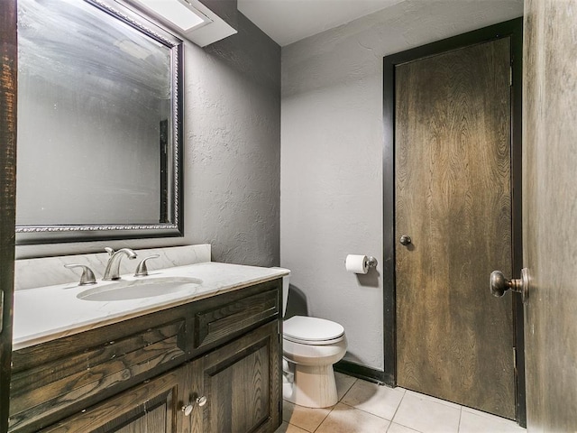 bathroom with toilet, vanity, and tile patterned floors