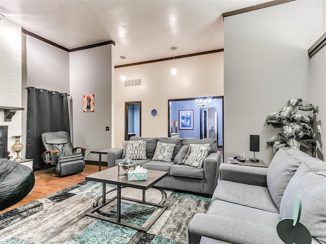 living room featuring a chandelier, wood-type flooring, crown molding, and a high ceiling