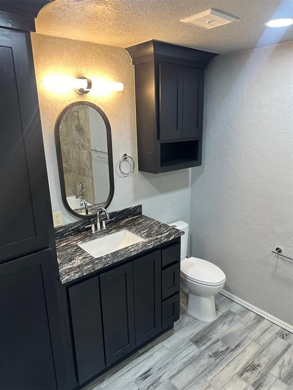 bathroom featuring hardwood / wood-style floors, vanity, toilet, and a textured ceiling