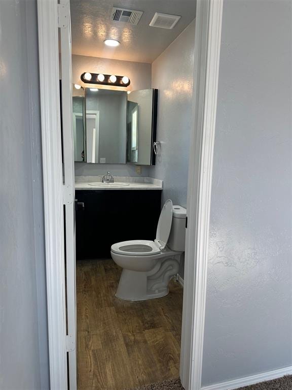 bathroom with hardwood / wood-style floors, vanity, and toilet