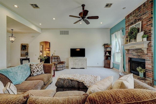 living room featuring a fireplace, ornamental molding, light carpet, and ceiling fan with notable chandelier