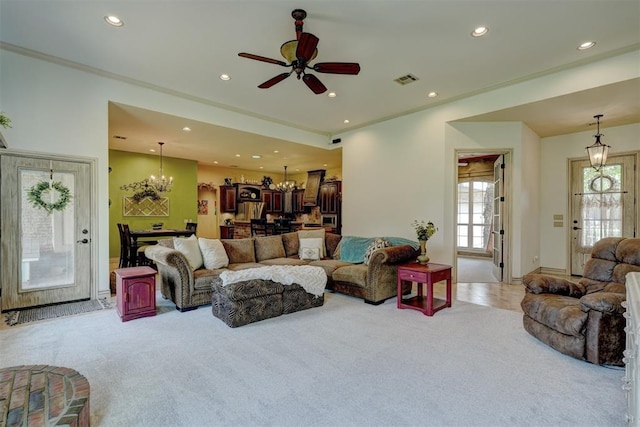 carpeted living room with ceiling fan with notable chandelier