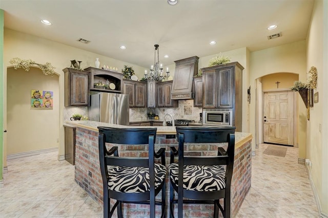 kitchen featuring custom exhaust hood, tasteful backsplash, a kitchen bar, dark brown cabinetry, and stainless steel appliances