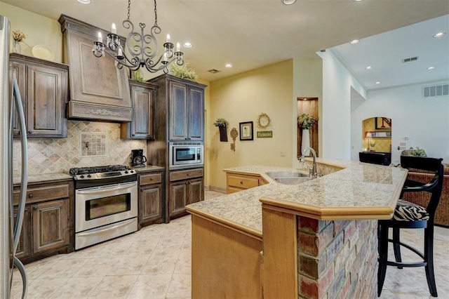 kitchen featuring sink, an island with sink, a chandelier, a breakfast bar, and appliances with stainless steel finishes