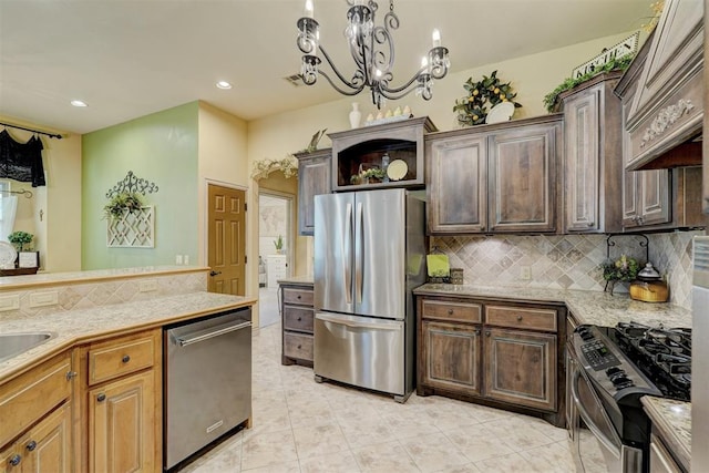 kitchen with appliances with stainless steel finishes, tasteful backsplash, custom exhaust hood, an inviting chandelier, and hanging light fixtures