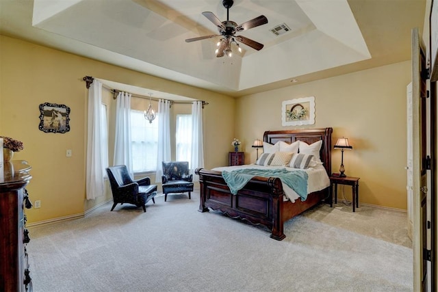 bedroom featuring light carpet, a raised ceiling, and ceiling fan