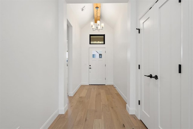 entryway featuring baseboards, visible vents, light wood-style flooring, vaulted ceiling, and a chandelier