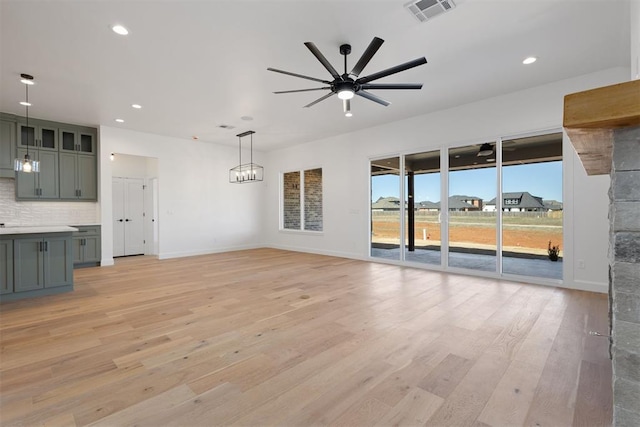 unfurnished living room featuring visible vents, baseboards, recessed lighting, ceiling fan with notable chandelier, and light wood-style floors