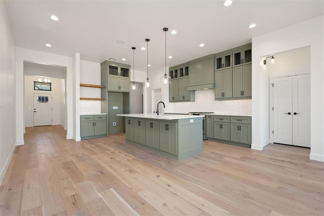 kitchen with green cabinets, light wood-type flooring, custom range hood, light countertops, and stainless steel gas range