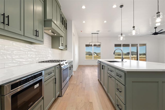 kitchen featuring a sink, backsplash, recessed lighting, appliances with stainless steel finishes, and light wood finished floors