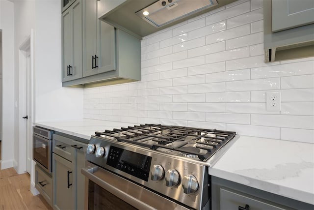 kitchen featuring custom exhaust hood, decorative backsplash, gas range, and gray cabinets