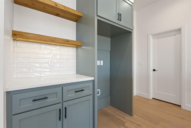 kitchen featuring open shelves, backsplash, light countertops, and light wood finished floors