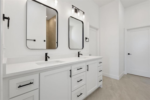 full bath featuring double vanity, baseboards, and a sink