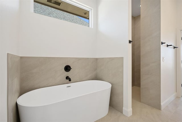 full bath featuring walk in shower, a freestanding bath, tile walls, and tile patterned flooring