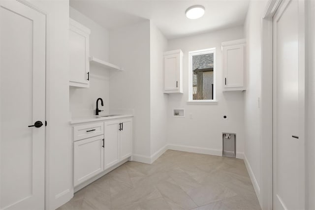 clothes washing area with a sink, cabinet space, baseboards, hookup for an electric dryer, and hookup for a washing machine