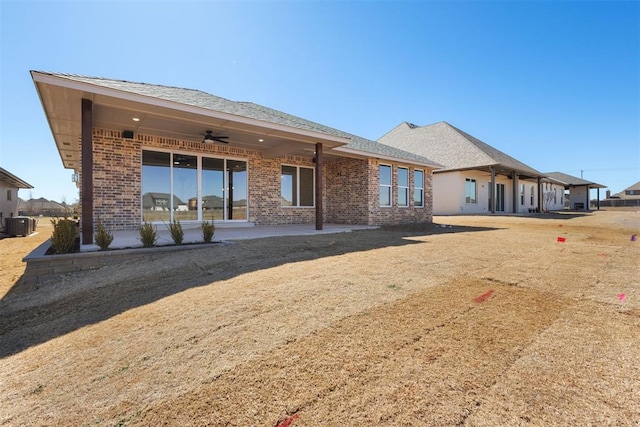 rear view of house featuring brick siding, a shingled roof, central AC, a patio area, and a ceiling fan