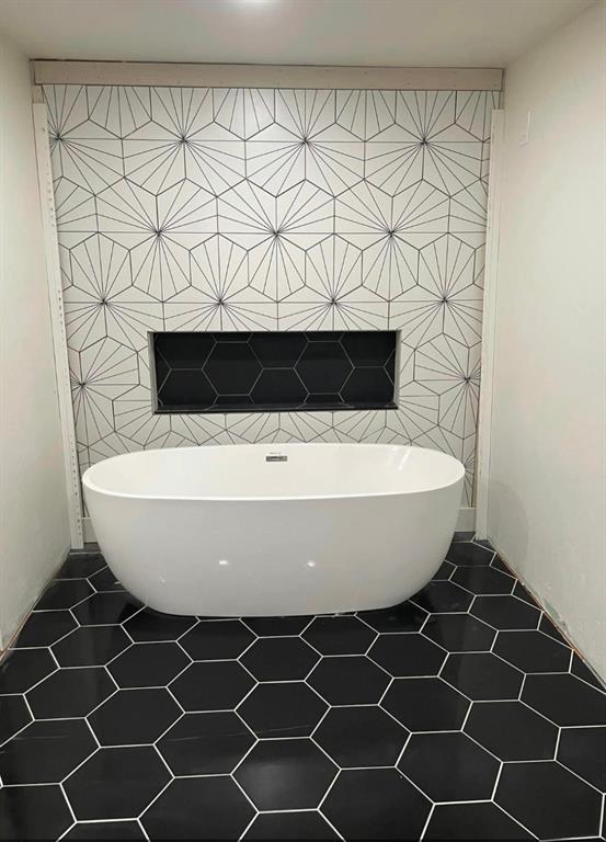 bathroom featuring tile patterned flooring, a tub to relax in, and tile walls