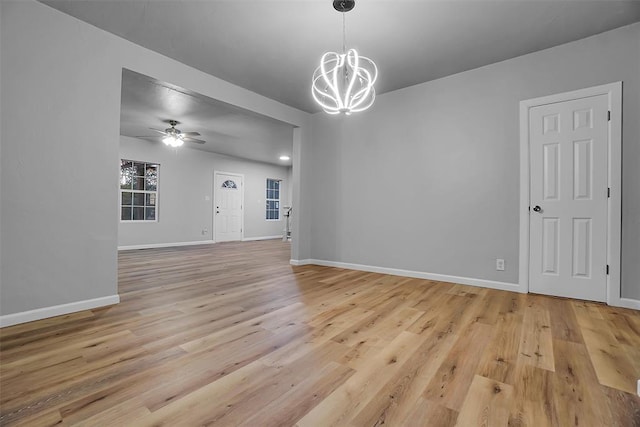 interior space with ceiling fan with notable chandelier and light hardwood / wood-style flooring