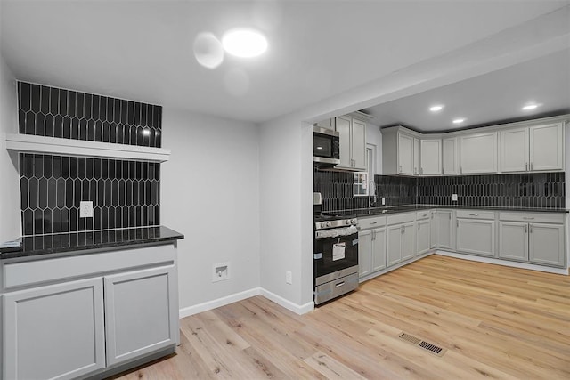 kitchen with tasteful backsplash, sink, stainless steel appliances, and light wood-type flooring