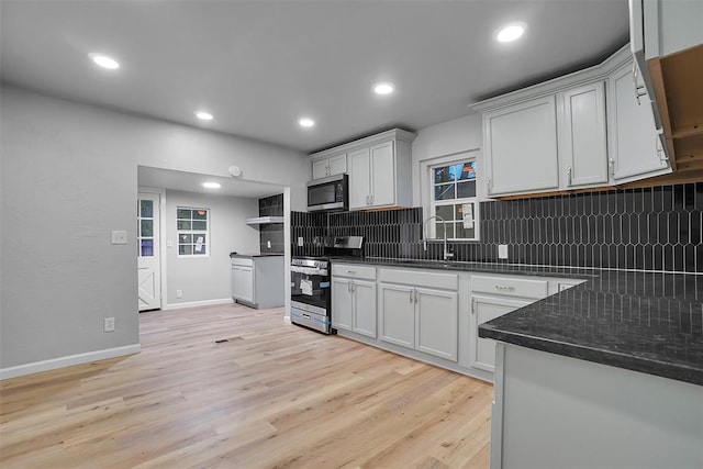 kitchen featuring white cabinets, light hardwood / wood-style floors, appliances with stainless steel finishes, and tasteful backsplash