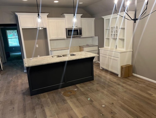 kitchen featuring white cabinets, dark wood-type flooring, an island with sink, and pendant lighting