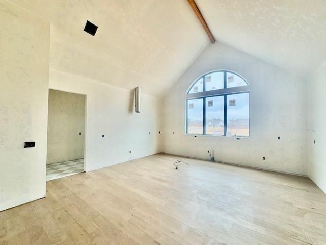 unfurnished living room with beam ceiling, high vaulted ceiling, and light hardwood / wood-style flooring