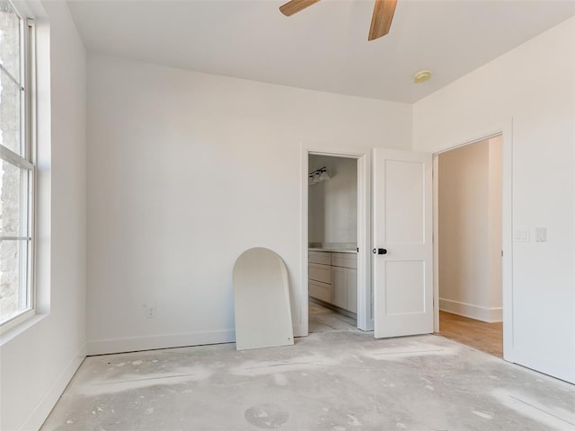 unfurnished bedroom featuring ensuite bathroom, concrete floors, and baseboards