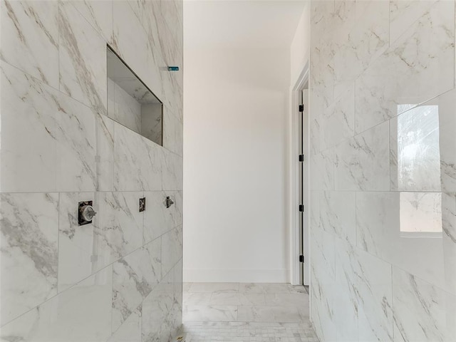 full bathroom with marble finish floor and a tile shower