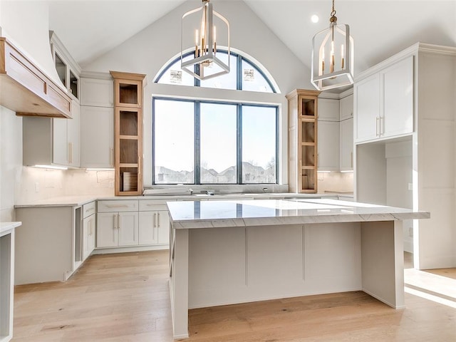 kitchen featuring an inviting chandelier, a kitchen island, open shelves, and light wood-style floors