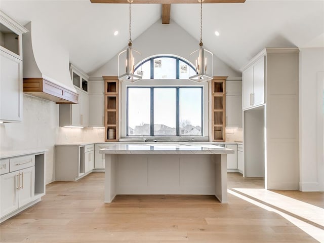 kitchen featuring open shelves, decorative backsplash, a kitchen island, a chandelier, and light wood-type flooring