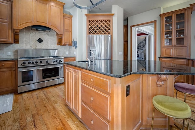 kitchen featuring backsplash, a kitchen island with sink, appliances with stainless steel finishes, and sink