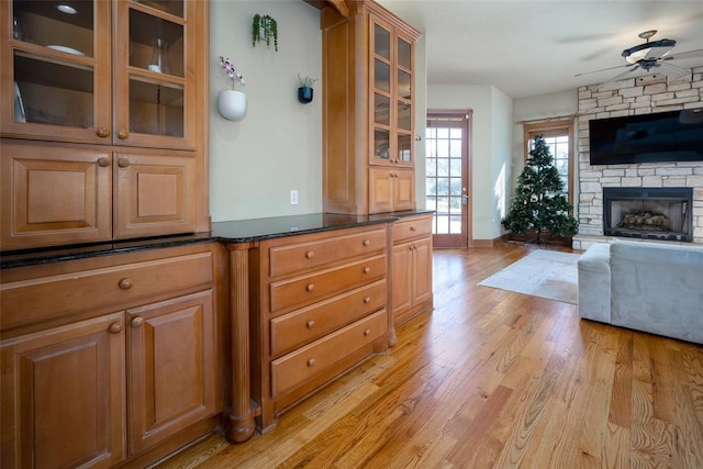 kitchen with ceiling fan, a fireplace, and light hardwood / wood-style flooring