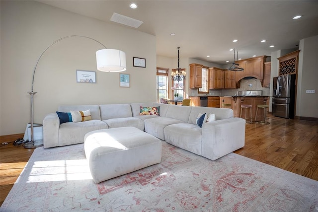 living room with a notable chandelier and light hardwood / wood-style flooring