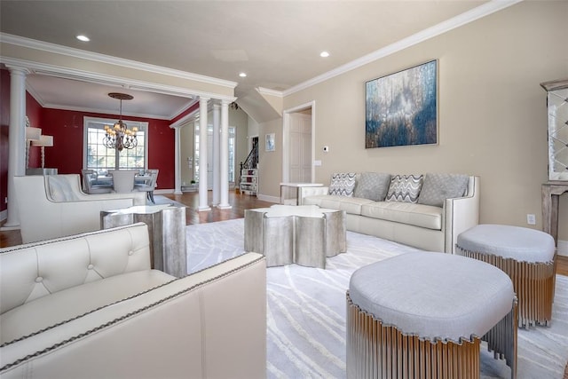 living room with light hardwood / wood-style flooring, a notable chandelier, crown molding, and decorative columns