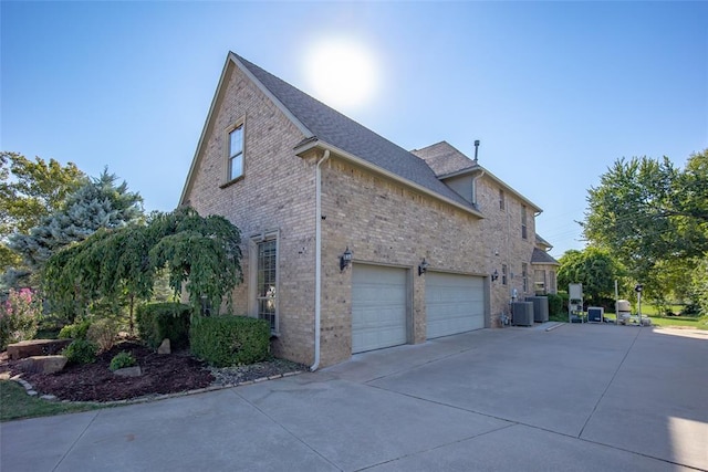 view of property exterior with central AC unit and a garage