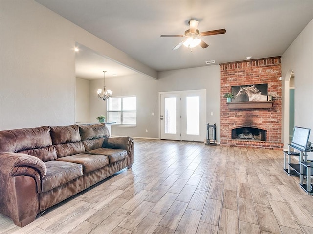 living room with a brick fireplace, ceiling fan with notable chandelier, and light hardwood / wood-style flooring