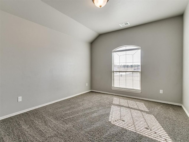 carpeted empty room featuring vaulted ceiling